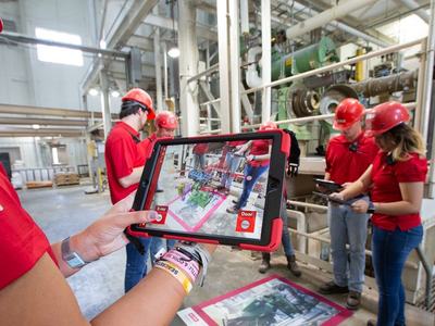 Four people hold ipads and interact with an AR pad in a feed mill