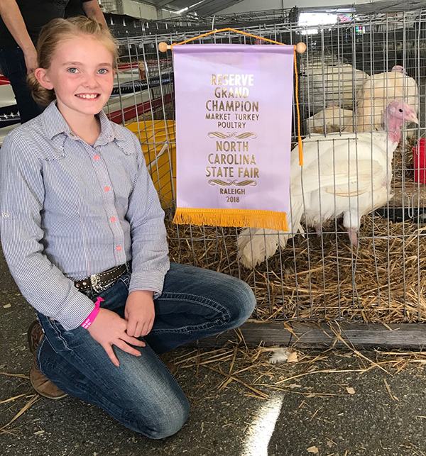 Caroline Scarlett kneeling beside her caged turkey