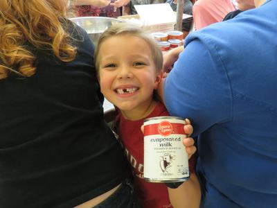 Child holding can labeled "Laura Lynn evaporated milk" between two adults