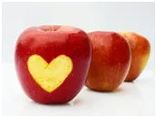 Red apple with yellow heart-shaped peel removed, two apples behind on white background