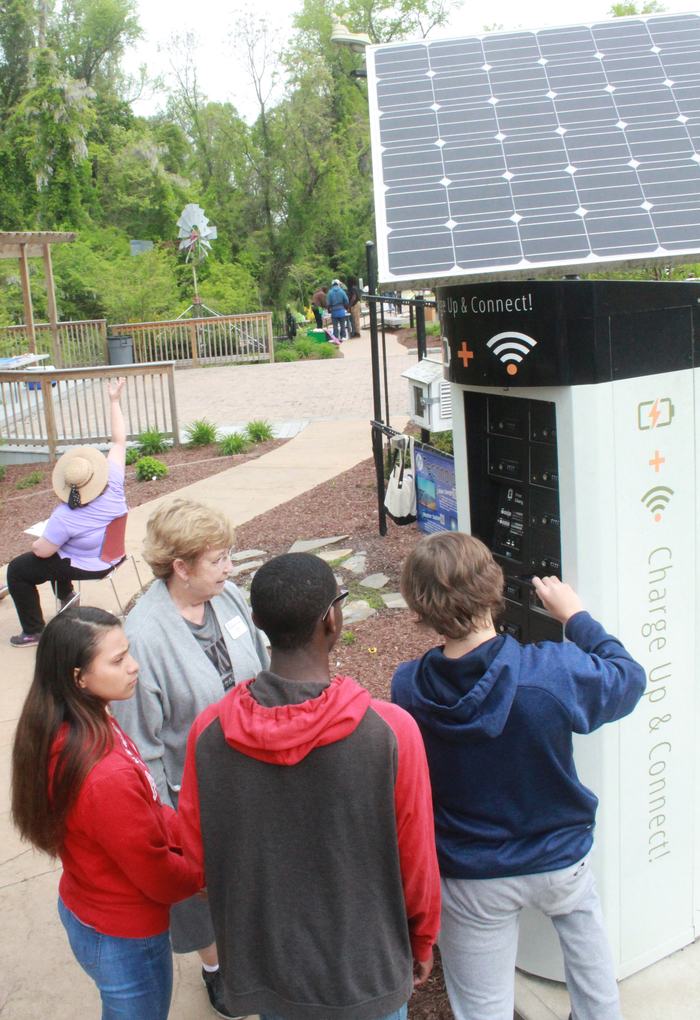students look at an outdoor, solar-powered charging station for devices