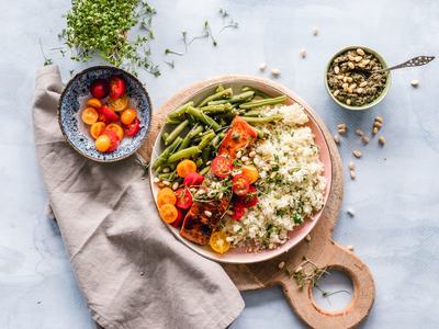 Bowl with grilled salmon, cauliflower rice, green beans, cherry tomatoes, and pine nuts