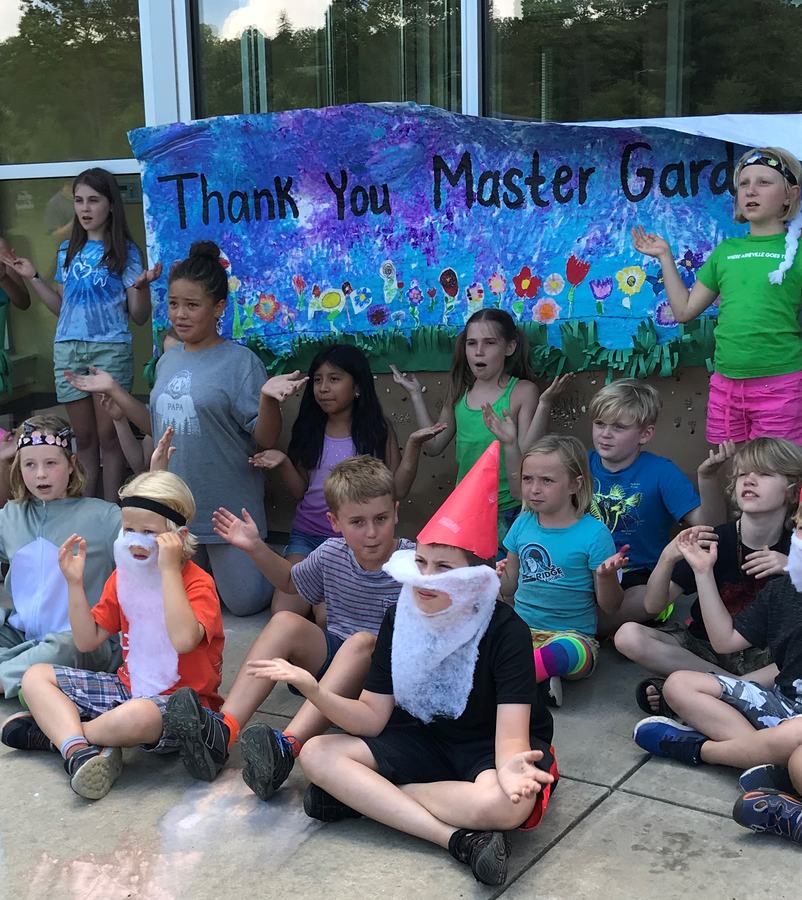 Kids seated outside in front of thank you banner.