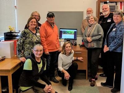 group of EMG volunteers stand near computer screen 