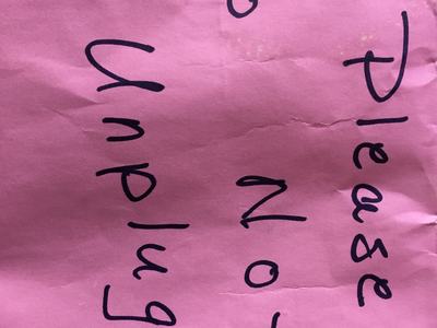 Pink paper with handwritten text: "Please do not unplug"