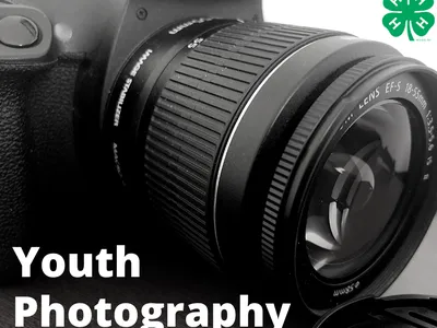 Close-up DSLR camera lens with text "Youth Photography" and 4-H clover logo