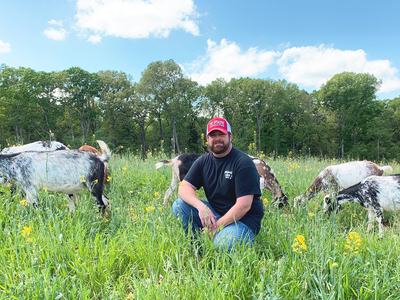 Jonas Asbill in a field with goats