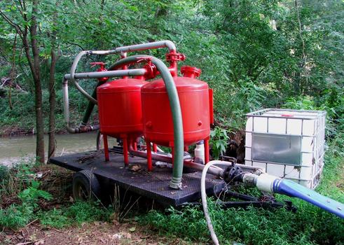 A trailer with sand filters next to a river where irrigation water is being pumped