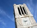 Top of the NC State University belltower with a bright blue sky in the background