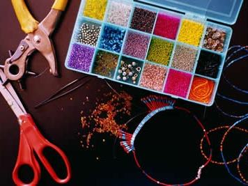 Bead organizer with colorful seed beads, spilled beads, pliers, scissors and beaded bracelets