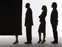 Three silhouetted professionals queued behind a voting booth curtain