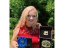Person holding blue ribbon labeled "North Carolina State" and open box with championship belt
