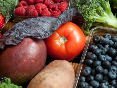 Assorted produce: raspberries, blueberries, tomato, sweet potato, mango, broccoli, kale