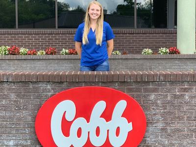 Sophie Chance standing behind the red and white Cobb sign