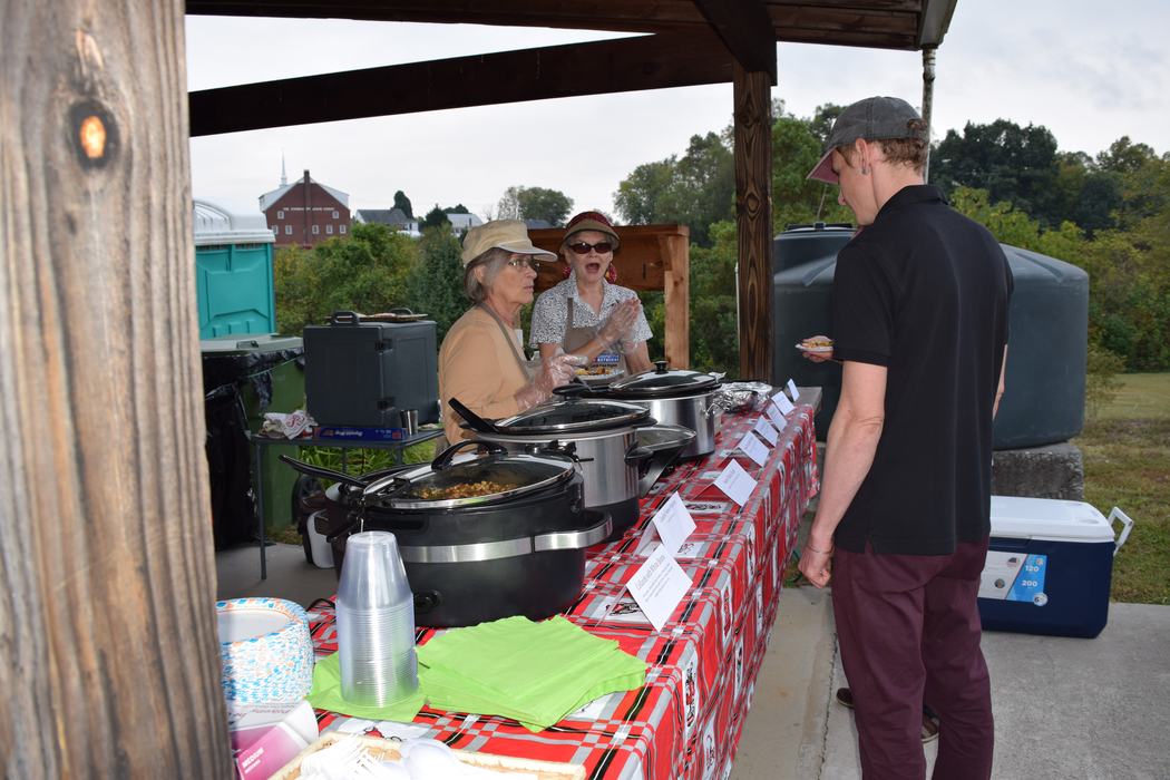 two volunteers speak with a visitor to the cooking demonstration table.