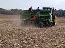 Two men on a John Deere tractor seeder planting across a harvested field