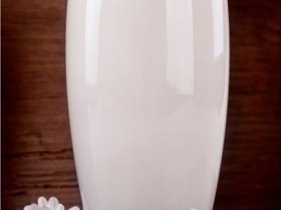 Tall glass of milk on wooden surface with four white daisies at its base