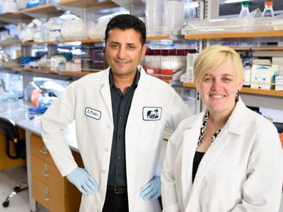 a man and a woman in lab coats and gloves stand together in a lab
