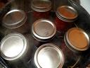 Seven mason jars with metal lids in a steaming water canner