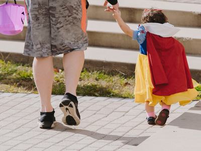 Child in costume holding an adult's hand