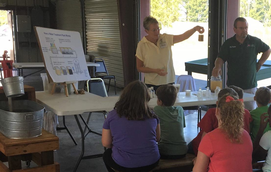 volunteer shows students a jar of muddy water