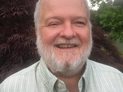 A man in a collared shirt smiling.