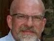 Bald man with glasses and trimmed white beard wearing a collared shirt, head-and-shoulders portrait
