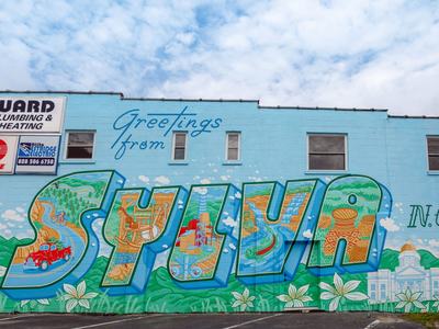 Mural reading "Greetings from SYLVA N.C." painted across a blue building