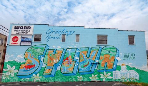 Mural reading "Greetings from SYLVA N.C." painted across a blue building