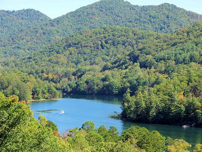Motorboat creating a wake on a lake surrounded by forested mountains