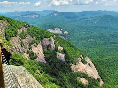 Cliffside overlook with wooden fence railing and forested mountain valley