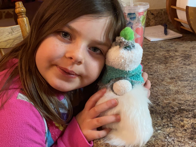 Young girl leaning on countertop holding a small plush gnome with white beard