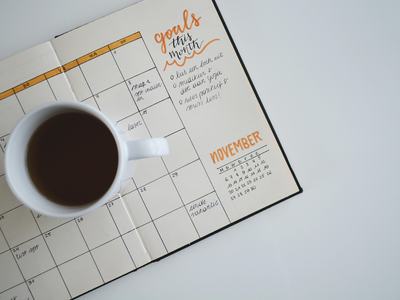 Coffee cup sitting on an open paper planner