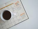 Coffee cup sitting on an open paper planner
