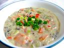 Bowl of creamy chowder with diced vegetables and chopped green onions