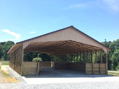 Open-sided wooden shelter with gabled metal roof on a gravel pad