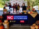 6 people standing behind a table that says NC Cooperative Extension