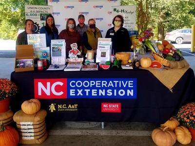 6 people standing behind a table that says NC Cooperative Extension