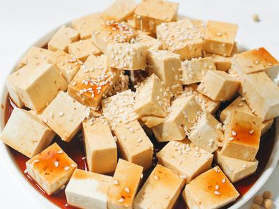 Small Square Blocks of Tofu Sitting in Soy Sauce with Sesame Seeds on Top