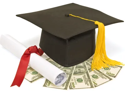 Graduation cap with yellow tassel and diploma tied with red ribbon resting on US $100 bills