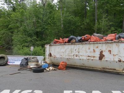 Rusty dumpster with orange and black trash bags, debris on ground; painted "NO PA"; 05/05/2018