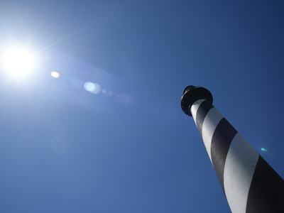 The Cape Hatteras Lighthouse stands as a beacon along the Outer Banks. The sun is lined up perfectly with the lighthouse.