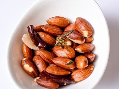 White bowl filled with raw almonds and dried chili pieces