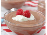 Glass bowl of chocolate mousse topped with whipped cream and two raspberries on red chevron napkin