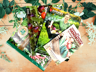 seed catalogs on a wooden table with flowers