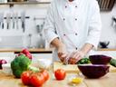 Chef of restaurant cooking fresh vegetable salad from green and red vegs