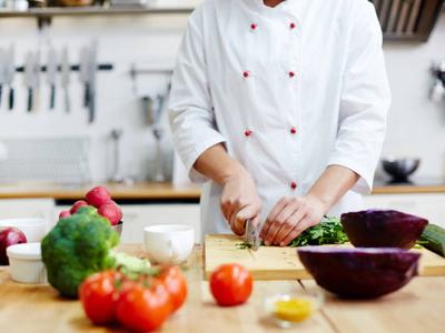 Chef of restaurant cooking fresh vegetable salad from green and red vegetables