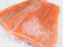 Two frozen salmon fillets with ice crystals sealed in plastic wrap