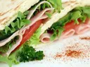 Ham and lettuce flatbread wrap with tomato slices and parsley garnish