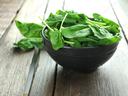 Fresh spinach in a wooden bowl on a wooden table